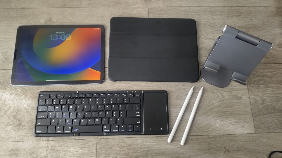 iPad Air 第5世代とケース、スタンド、折りたたみキーボード、スタイラスペンを並べた様子