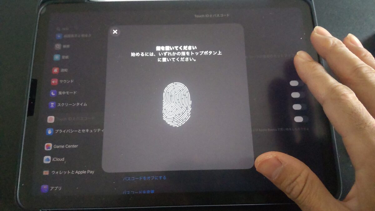 iPad Airのトップボタンに指を置いてTouch IDの指紋を登録している様子